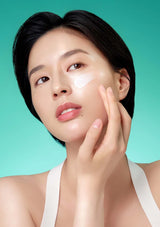 Woman applying cream to her face against a teal background