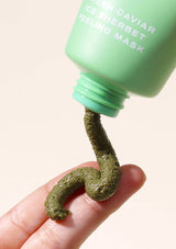 Green caviar peeling mask being squeezed from a green bottle onto a hand.