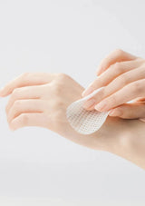 Person applying a white adhesive patch to their wrist on a light background