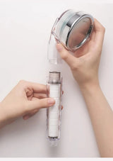 Hands separating the BODYLUV Vita Puresome shower head from its handle to access the white Puresome filter.