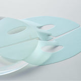 Authentic DERMAFIX Hyal two-piece blue hydrogel mask on glass.