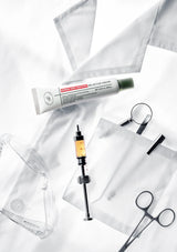 Skincare products including a tube, syringe, and scissors on a white background