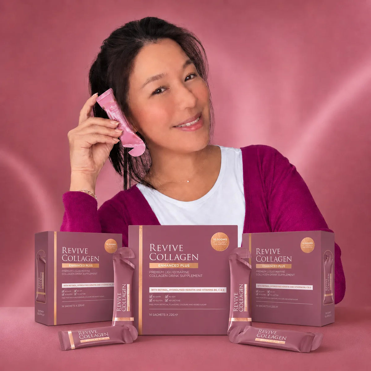 Woman holding a Revive Collagen sachet behind three Revive Collagen boxes