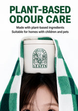 A person wrapped in a green and white checkered towel has their face partially covered, with a white cylindrical canister of LEAFIN plant-based odor care placed on their forehead. Large green and black text at the top reads 'PLANT-BASED ODOUR CARE' and 'Suitable for homes with children and pets'.