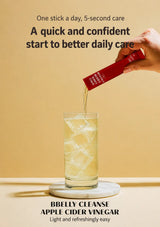 A hand pours a red BBelly Cleanse Apple Cider Vinegar stick packet into a glass of apple cider vinegar with ice, set against a warm beige background with promotional text.