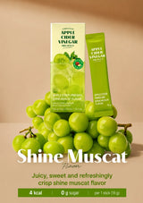 Shine Muscat apple cider vinegar flavor product packaging shown with a box and a single stick pack, styled with green grapes on a warm beige background. Large text reads 'Shine Muscat Flavor' and smaller text describes the flavor as juicy, sweet, and refreshing.