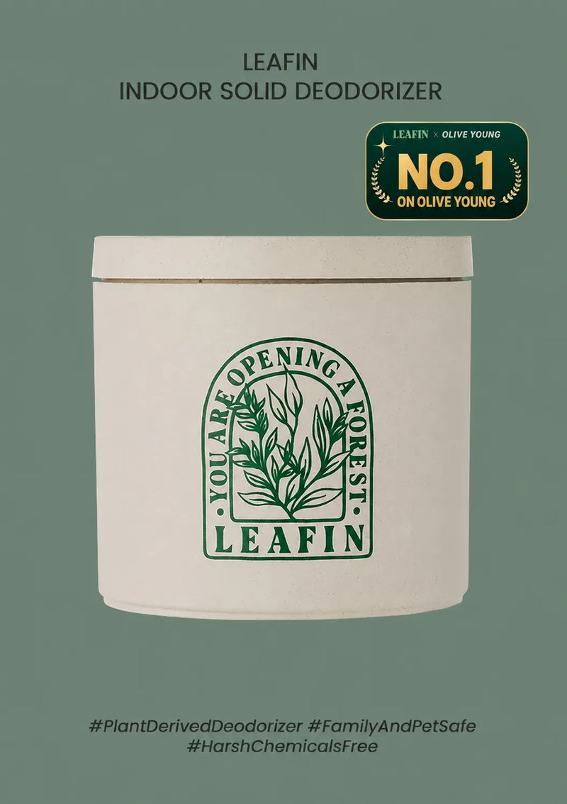 A white cylindrical tin of LEAFIN Indoor Solid Deodorizer on a muted sage green background. The tin features a green botanical logo with the text 'You Are Opening a Forest' and 'LEAFIN'.