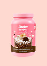 A pink container of Shake Baby Protein Shake in Marshmallow Chocolate flavor, shown against a solid pale pink background.