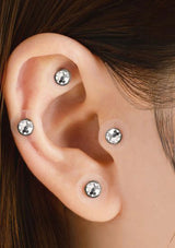 Close-up of an ear with three diamond stud earrings.