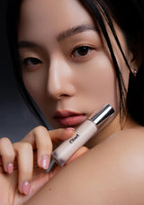Woman holding a makeup product with a dark background
