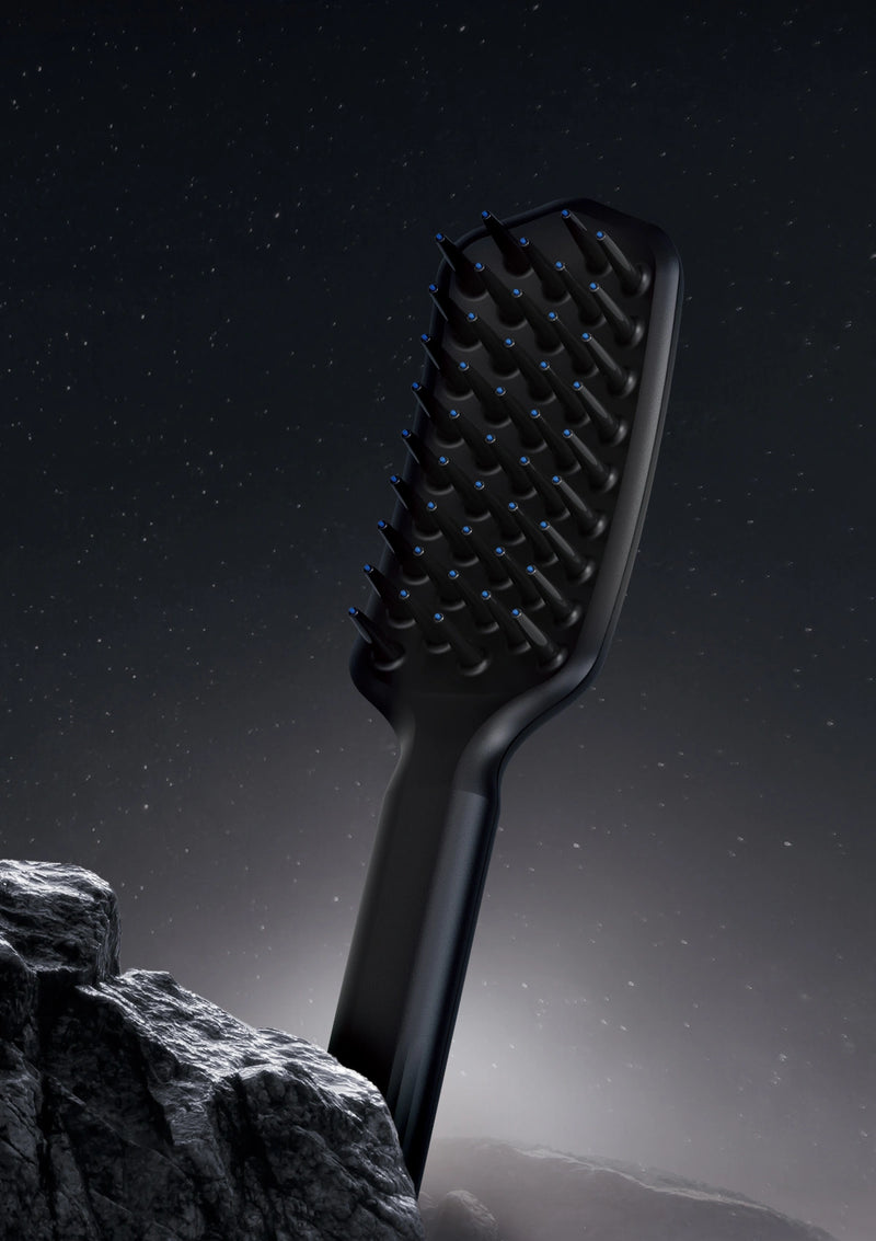 Black hairbrush on a rocky surface with a dark sky background