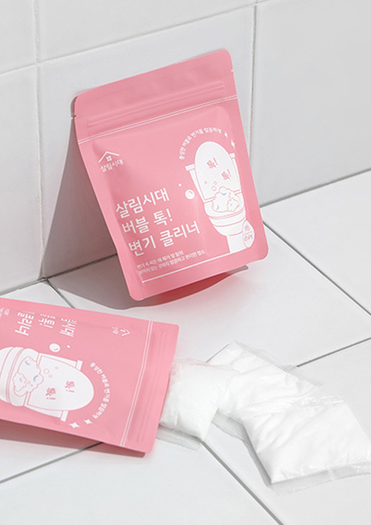 Two pink packaging bags with a cartoon character on a white tiled floor.
