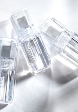 Clear skincare bottles on a reflective surface