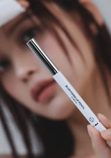 Person holding a white lip pencil with a blurred background