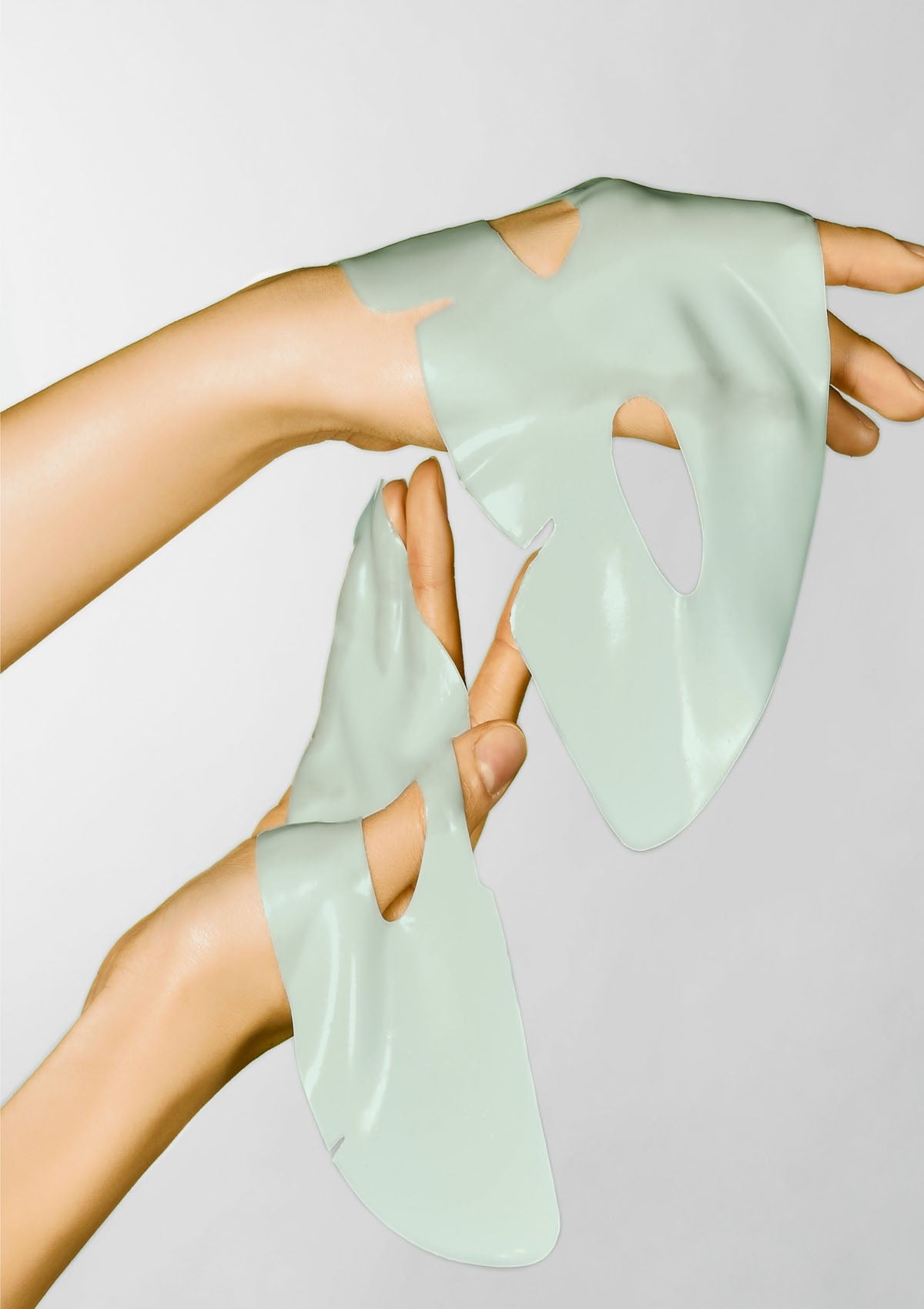 Person wearing light green silicone gloves on a plain background