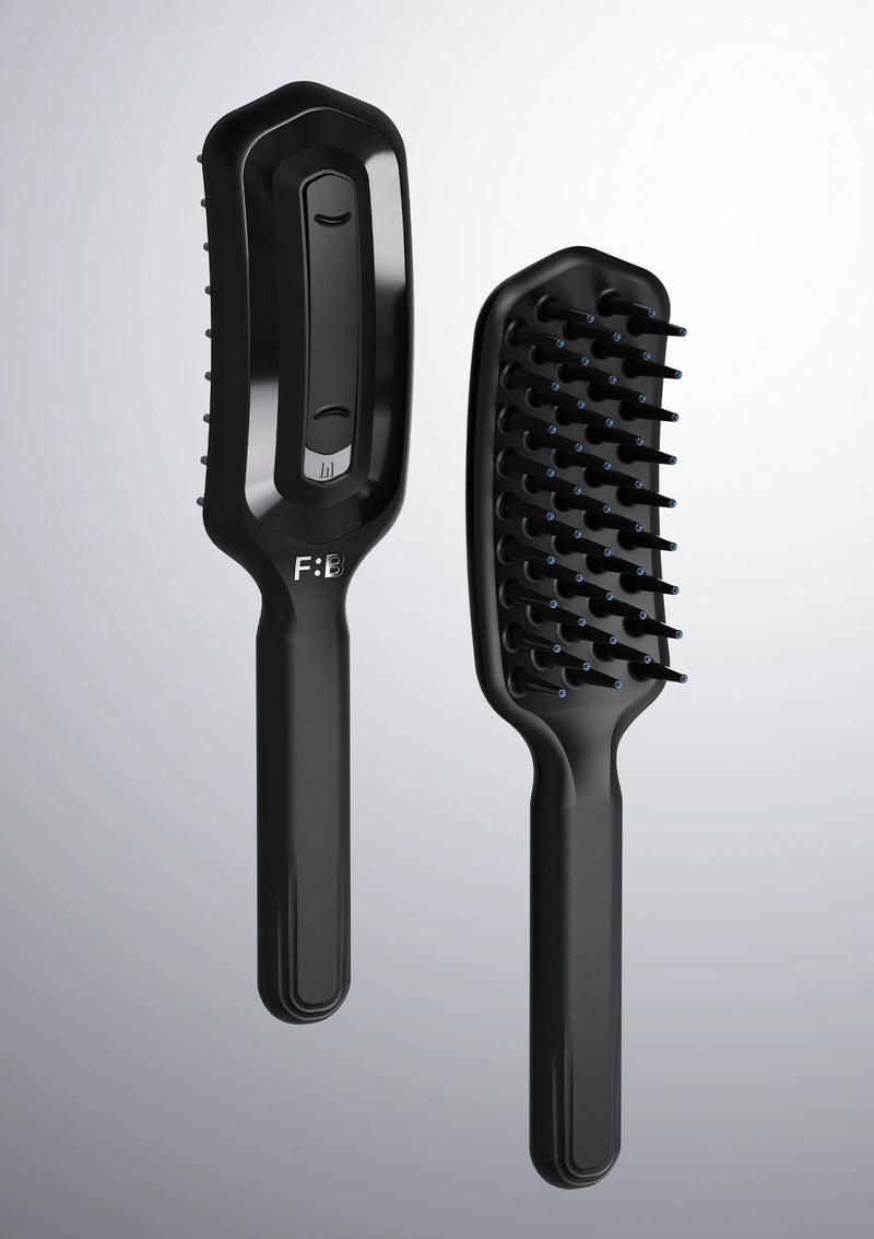 Black hairbrush with bristle head and handle on a gray background