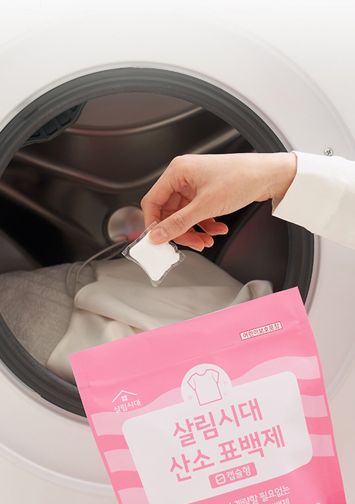 Person placing a white packet into a washing machine with a pink package labeled '氧白包' in front.