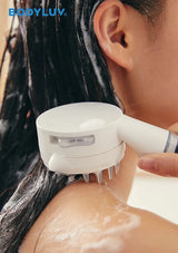 A close-up of a person receiving a neck and shoulder scalp massage treatment with a white handheld device branded BODYLUV. The person has wet, dark hair, and the device is shown applying pressure with soap lather on the skin.
